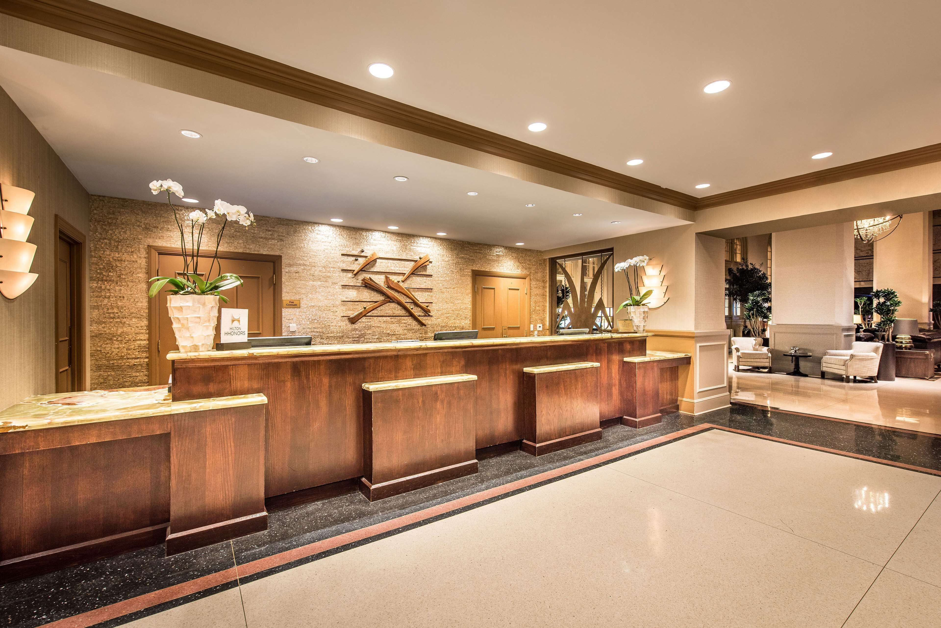 A reception area with a wooden reception desk, a wall-mounted sculpture, and a large mirror.