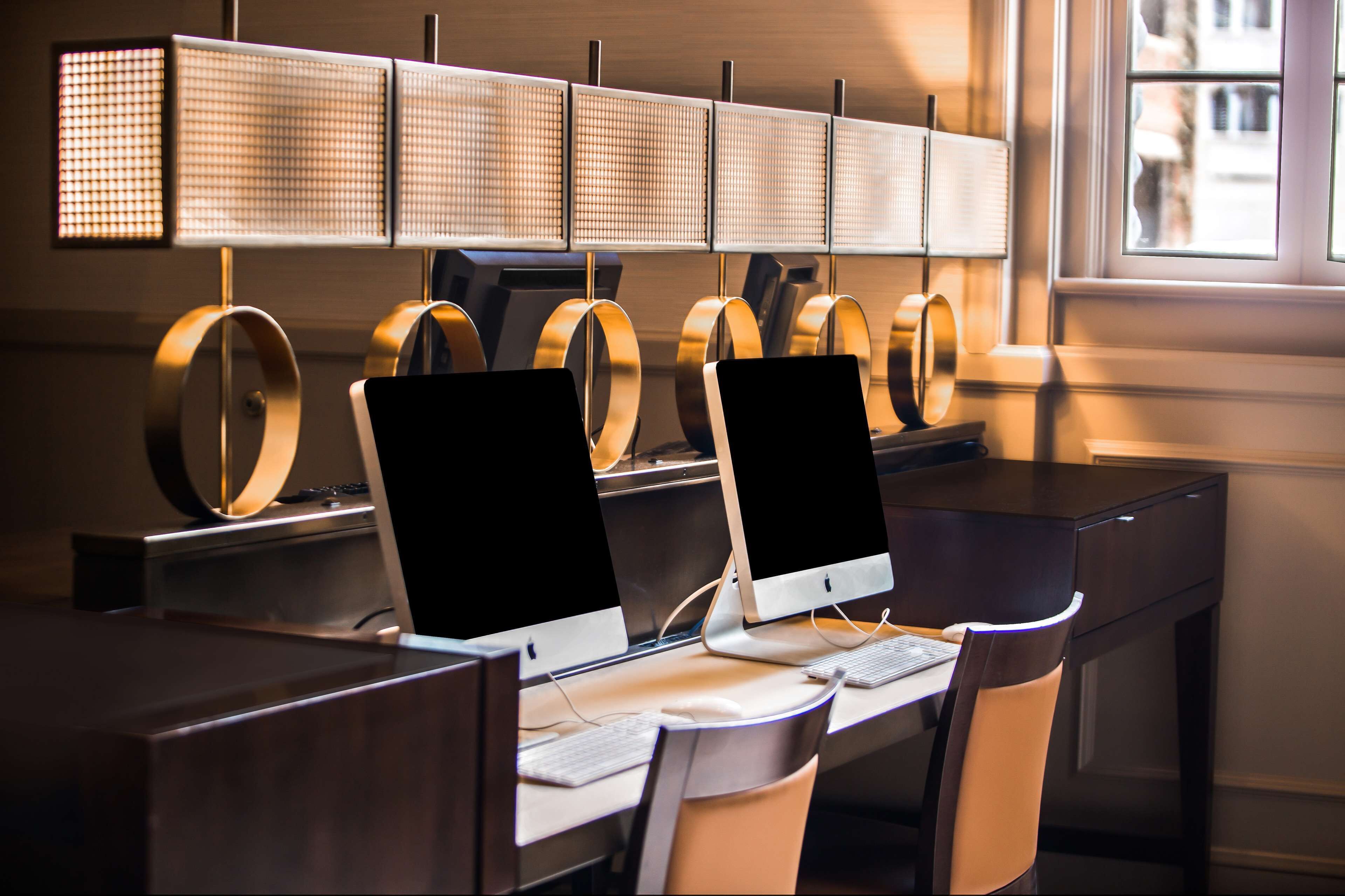 Ein moderner Arbeitsplatz mit mehreren Apple iMac Computern, ergonomischen Stühlen und einer ungewöhnlichen Lichtleuchte.