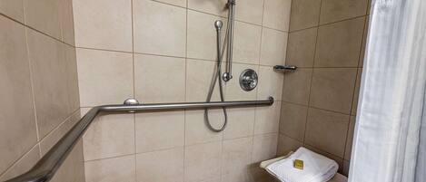 Un espace douche équipé d’une barre d’appui, d’un pommeau de douche et d’un porte-serviettes.