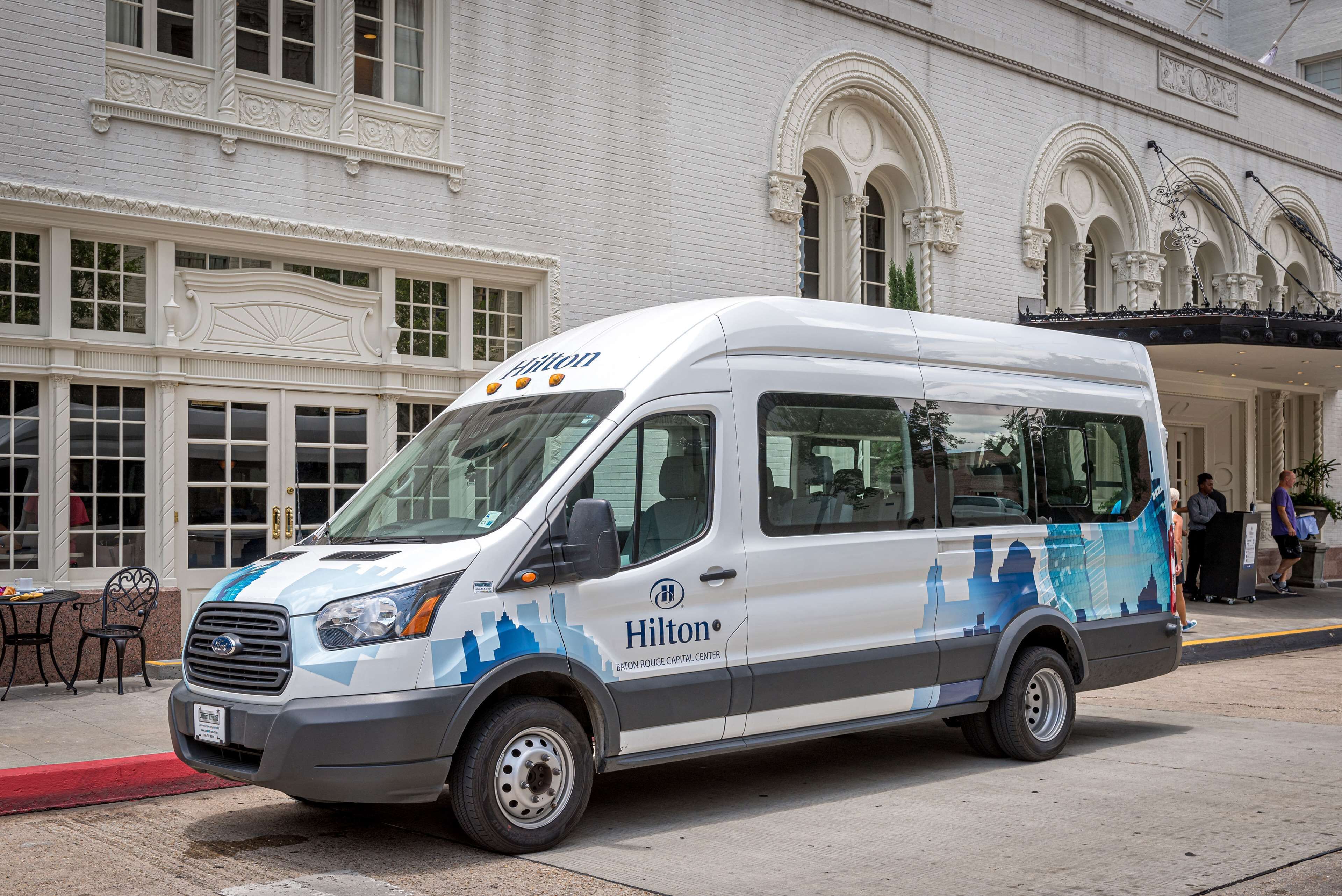 A white and blue van parked in front of a building with ornate architecture.
