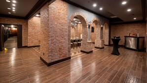 A spacious room with brick walls, wooden flooring, and a bar area. - Hilton Baton Rouge Capitol Center (Baton Rouge)