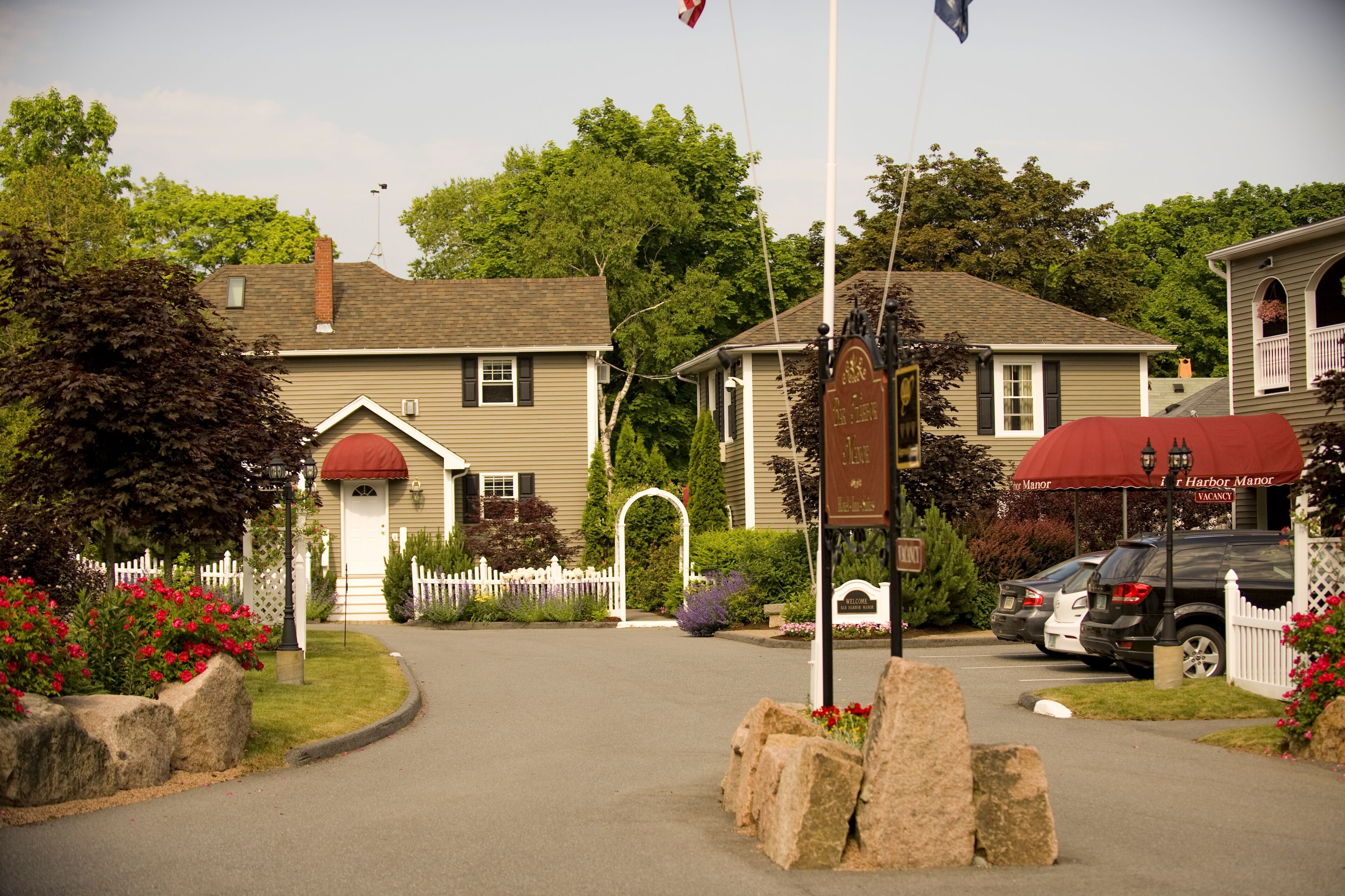 A hotel entrance with a white picket fence, a red awning, and a sign indicating a vacancy.