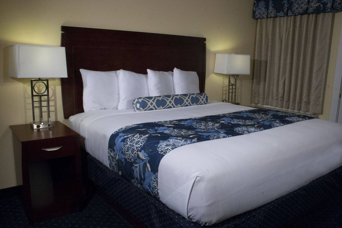 A hotel room with a large bed, two bedside tables, and a nightstand.