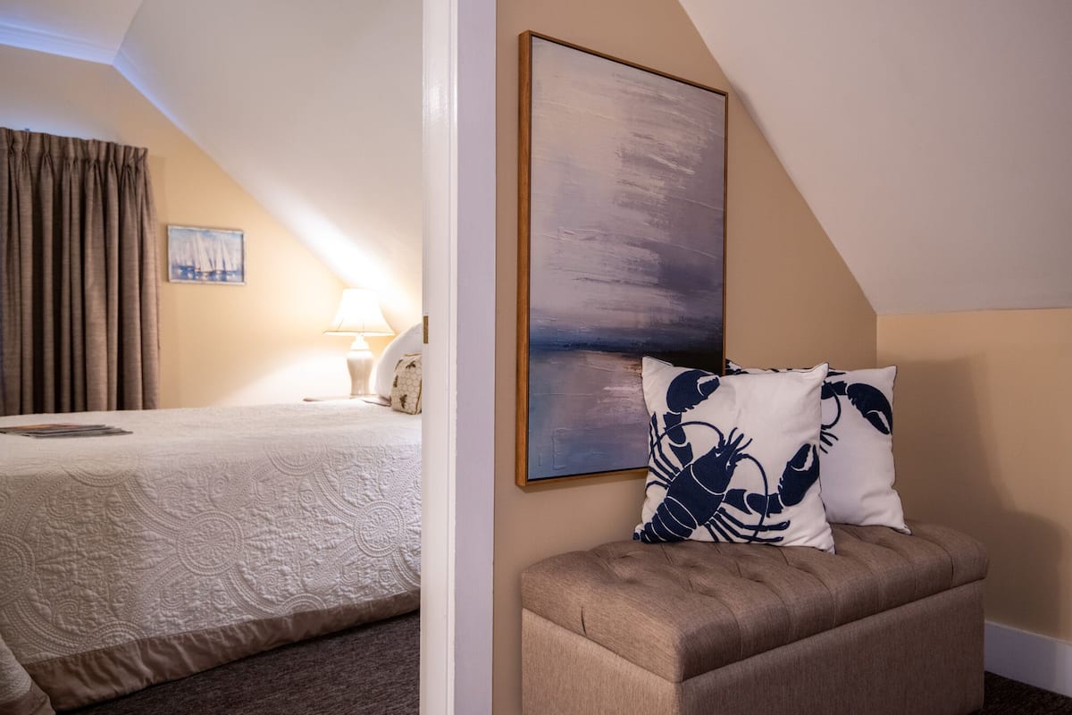 A hotel room with a bed, a couch, a painting, and a lamp.