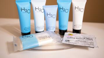 Five H2O Therapy products, including shampoo, conditioner, body wash, shampoo, and body lotion, along with a massage bar and makeup remover wipes.