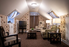 A cozy loft bedroom with a large bed, a TV, and a window with curtains.
