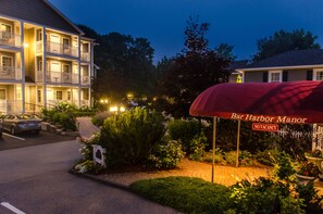 Un hotel de varios pisos con un espacio de estar al aire libre cubierto, un estacionamiento y un jardín ajardinado.