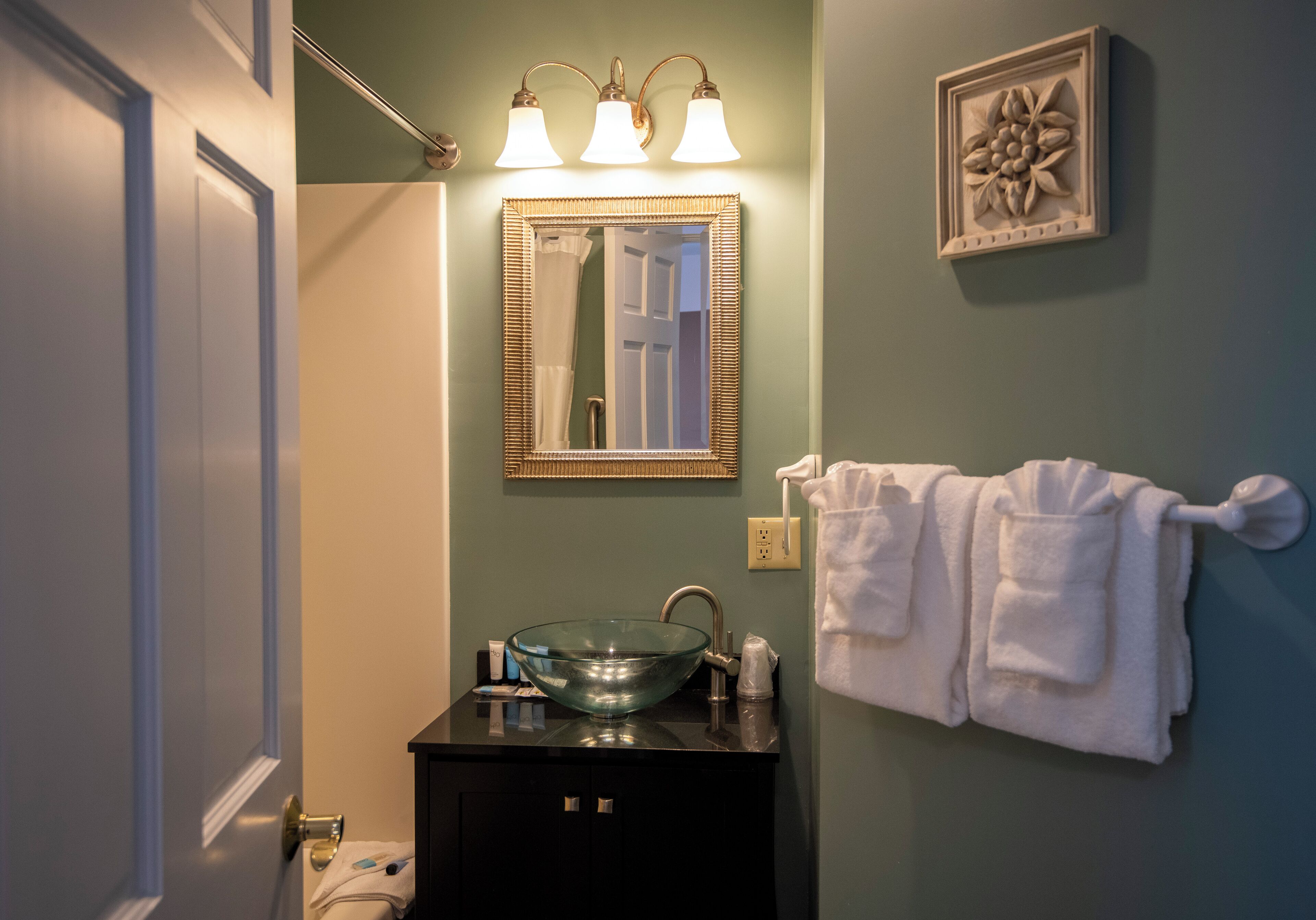 A bathroom with a glass bowl sink, a mirror, and a towel rack.
