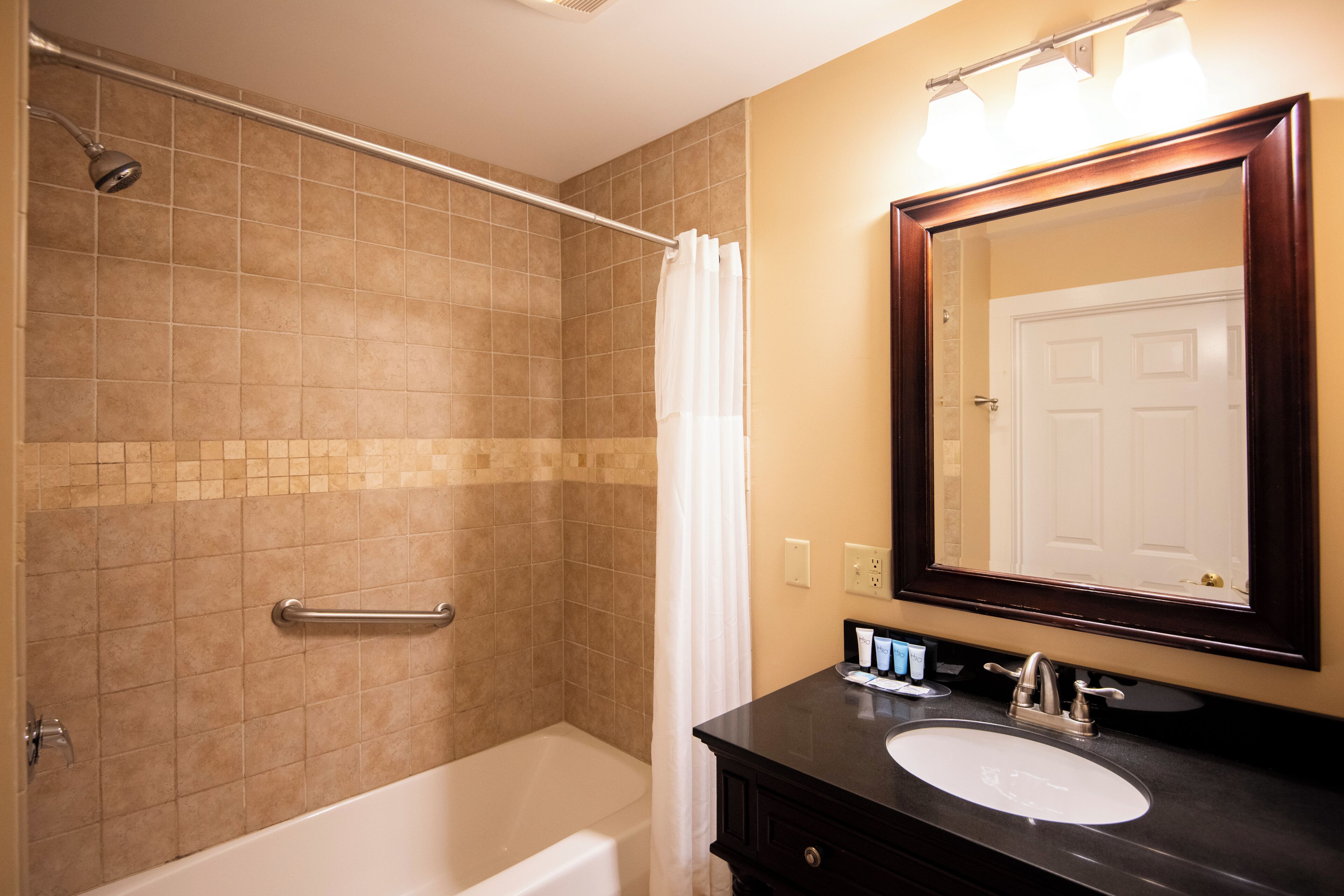 A bathroom with a bathtub, a shower, a sink, and a mirror.