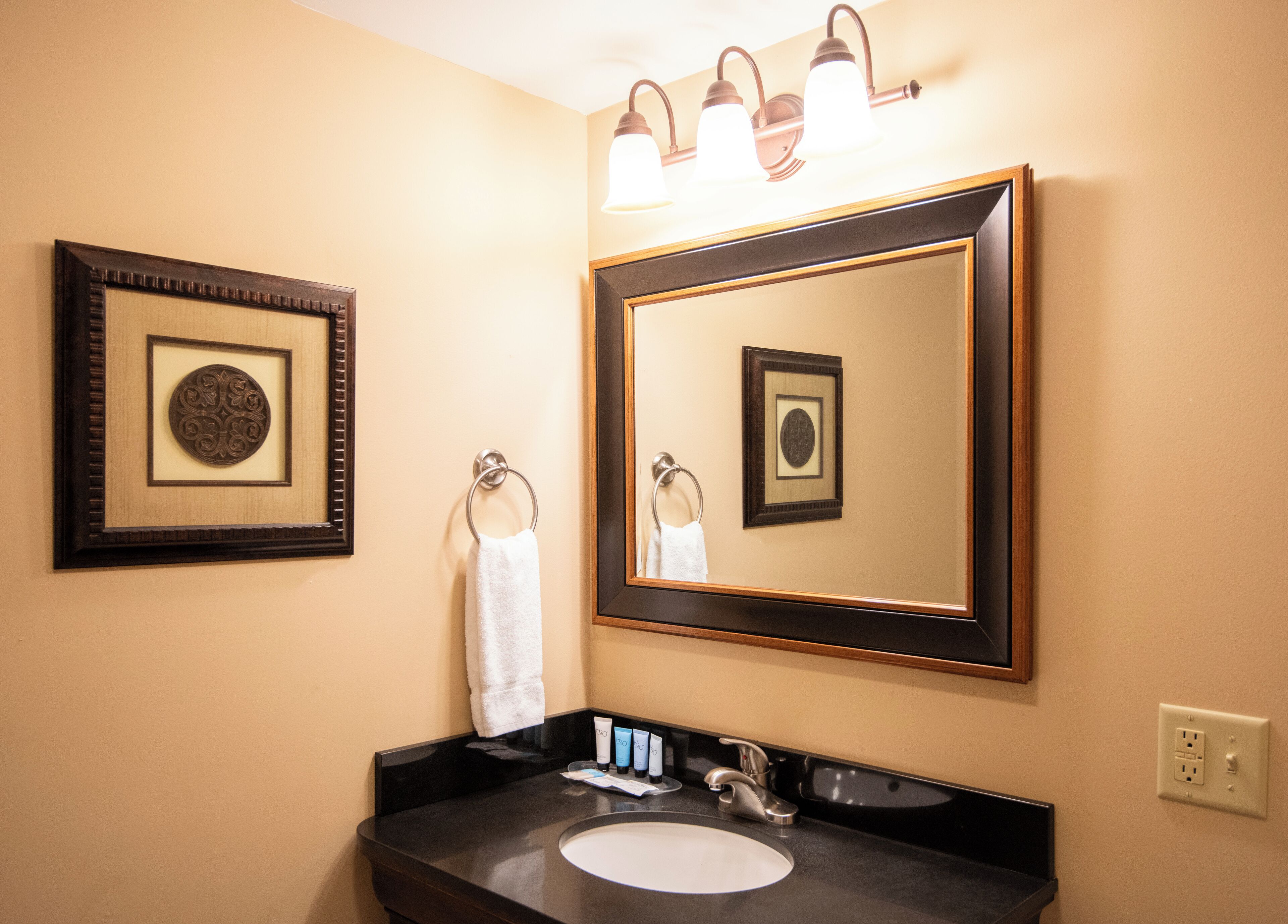 A bathroom with a large mirror, a sink, and a towel rack.