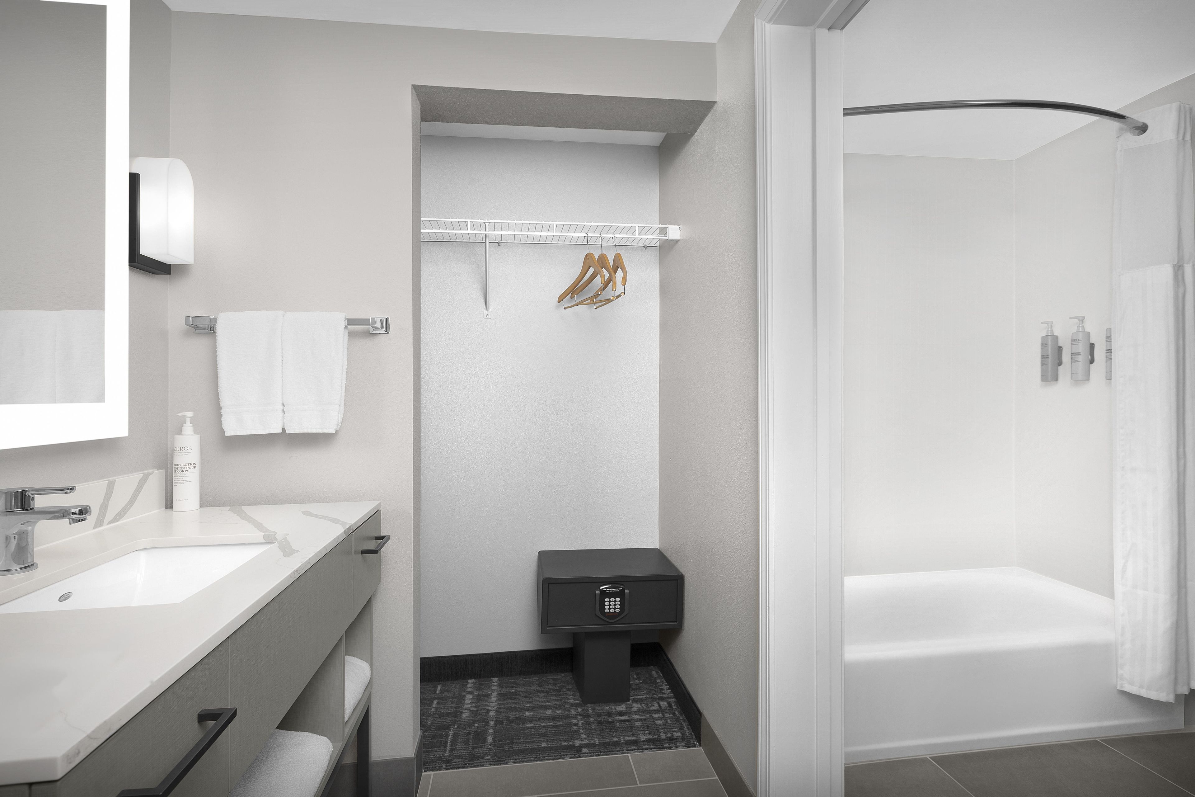 A modern bathroom with a white sink, mirror, and a shower area.