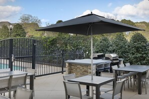 An outdoor patio area with a pool, a grill, and a seating arrangement.