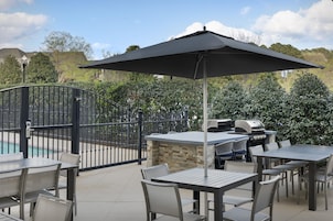 An outdoor patio area with a pool, a grill, and a seating arrangement.