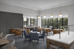 Un interior moderno con diversas opciones de asientos, ventanas amplias e iluminación colgante.