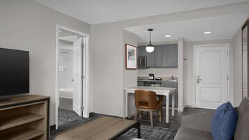 A compact hotel room with a bed, a television, a desk, and a kitchenette.