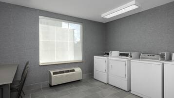 A laundry room with a large window, a wall-mounted heater, and stacked laundry machines.