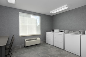 A laundry room with a large window, a wall-mounted heater, and stacked laundry machines.