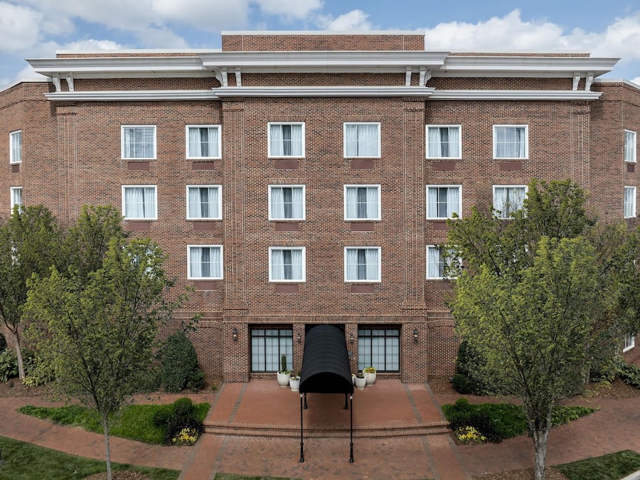 A multi-story brick building with a symmetrical facade, evenly spaced windows, and a central entrance with a canopy.