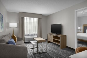 Habitación de hotel con sofá, escritorio, silla, televisor y cama.