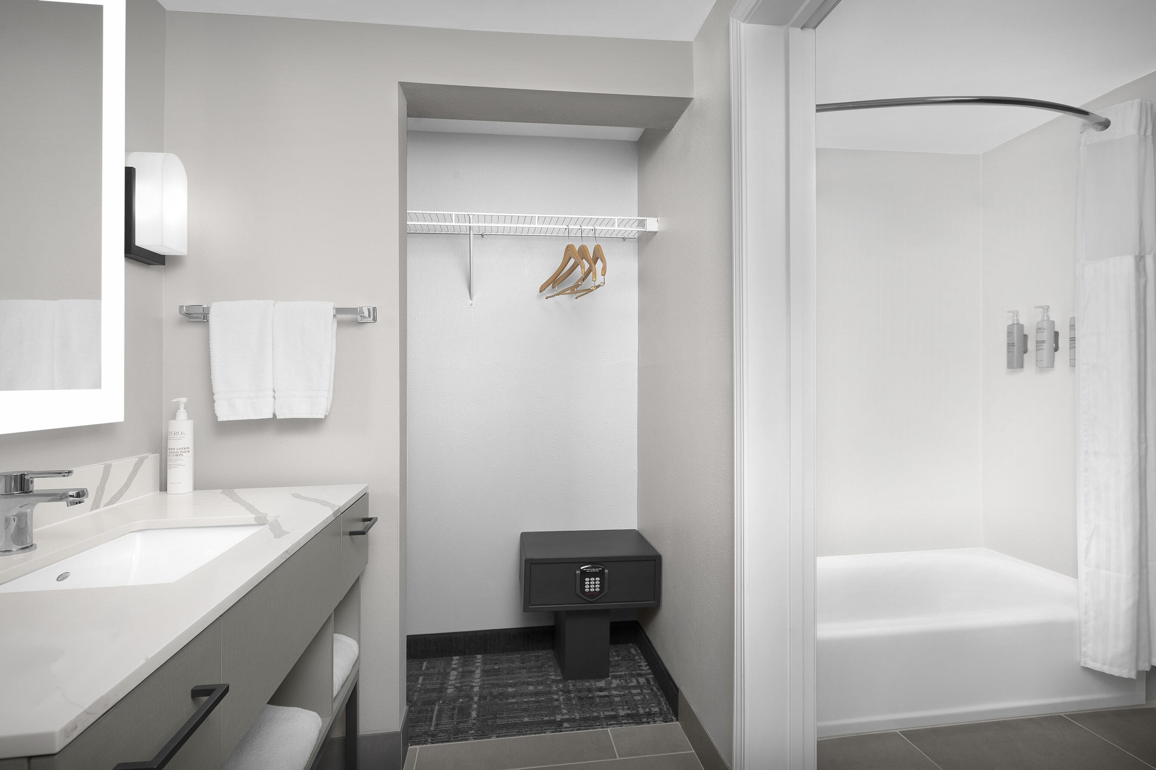 A modern bathroom with a white sink, a toilet, a shower, and a towel rack.