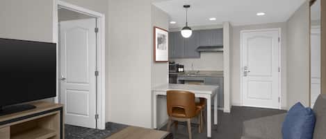 A compact living space with a television, a dining area, and a kitchenette.