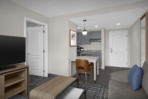 Un espacio habitable compacto con televisor, comedor y kitchenette.