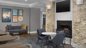 A modern living room with a fireplace, a sofa, and a TV mounted on the wall.