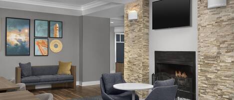 Un salon moderne avec une cheminée, un canapé et un téléviseur fixé au mur.