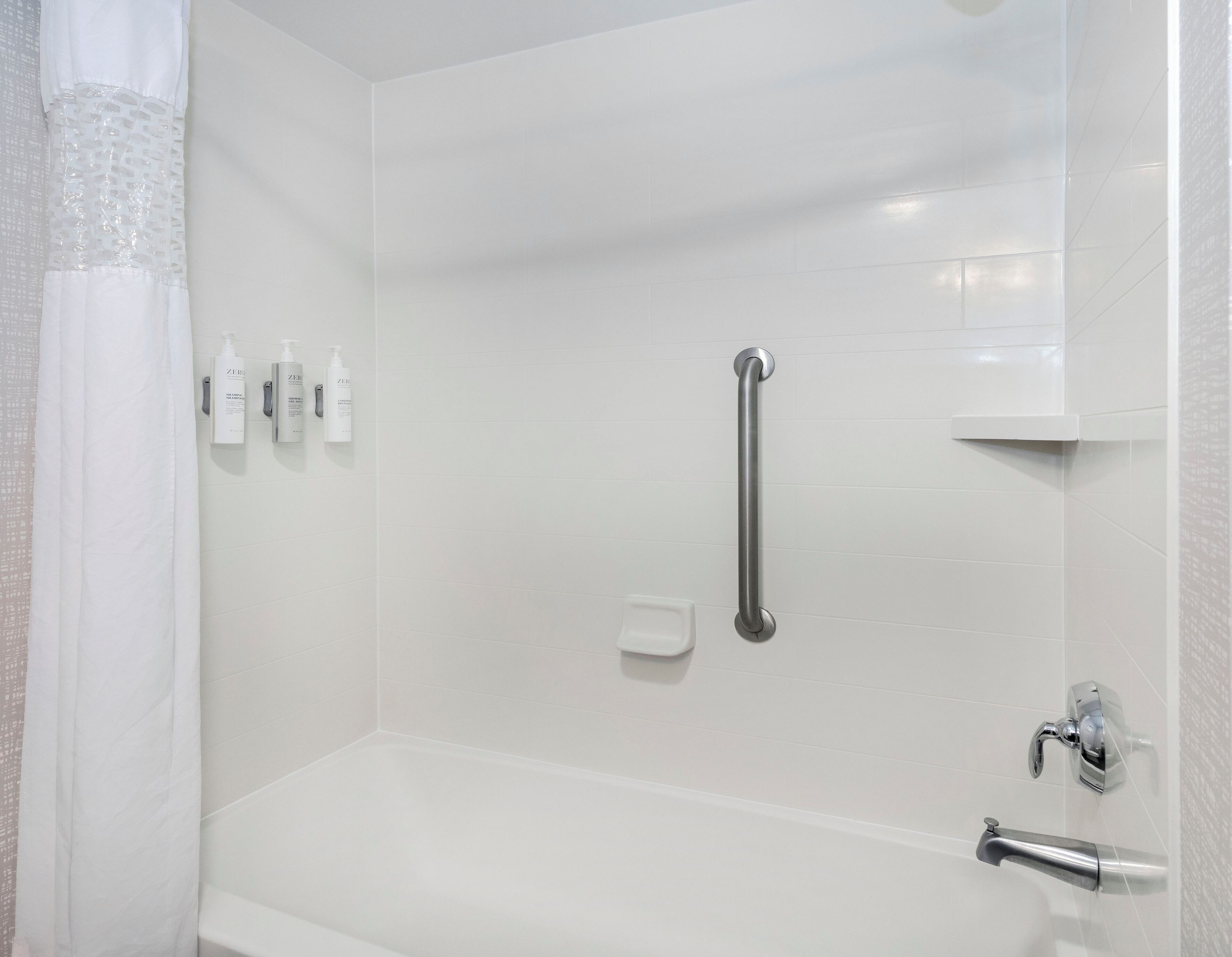 A modern bathroom with a walk-in shower, a grab bar, and a handheld showerhead.