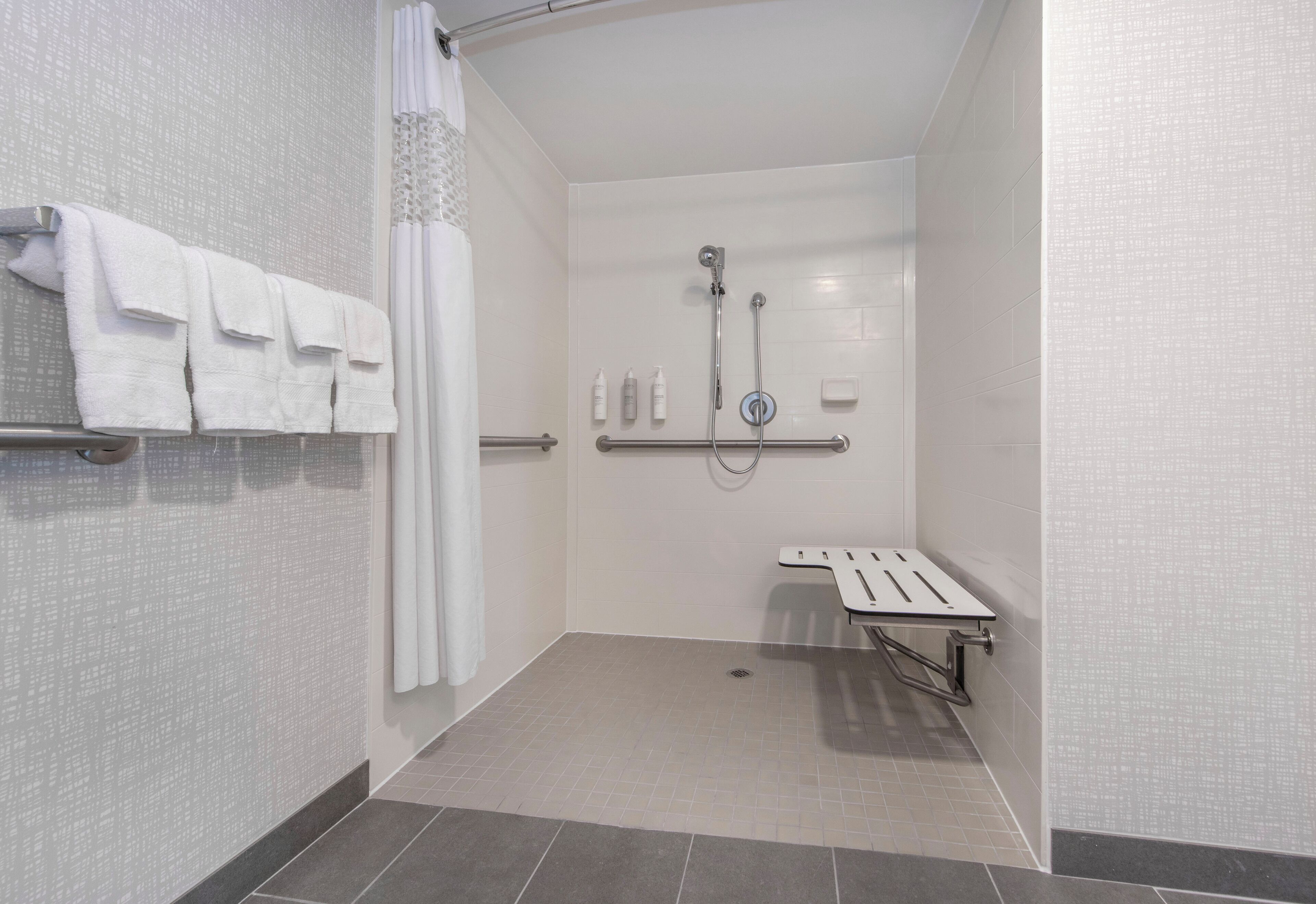 Une salle de bain moderne équipée d’une douche, de barres d’appui et d’un porte-serviettes.