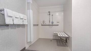 Une salle de bain moderne équipée d’une douche, de barres d’appui et d’un porte-serviettes.