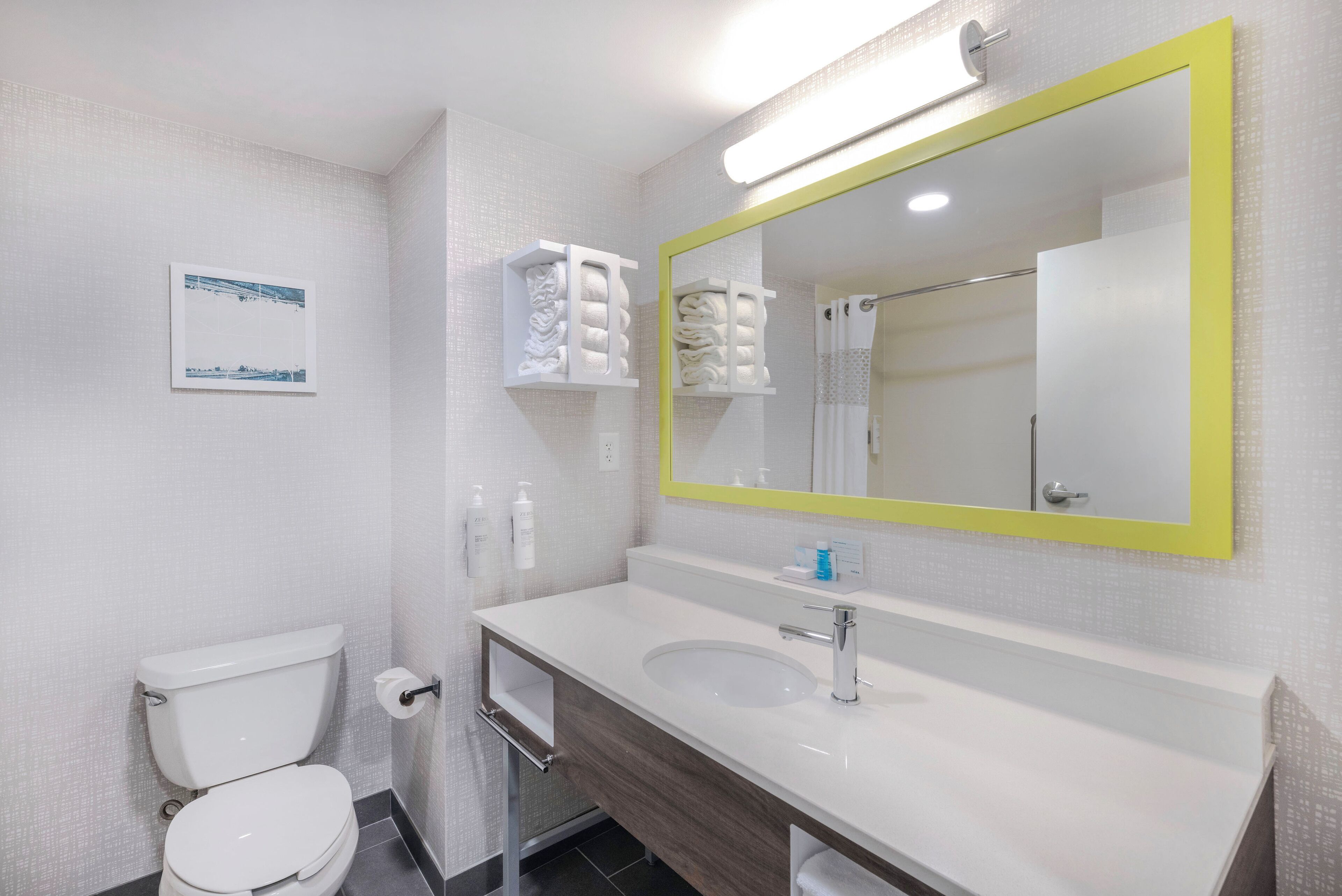 A bathroom with a white toilet, a sink with a mirror, and towel racks.