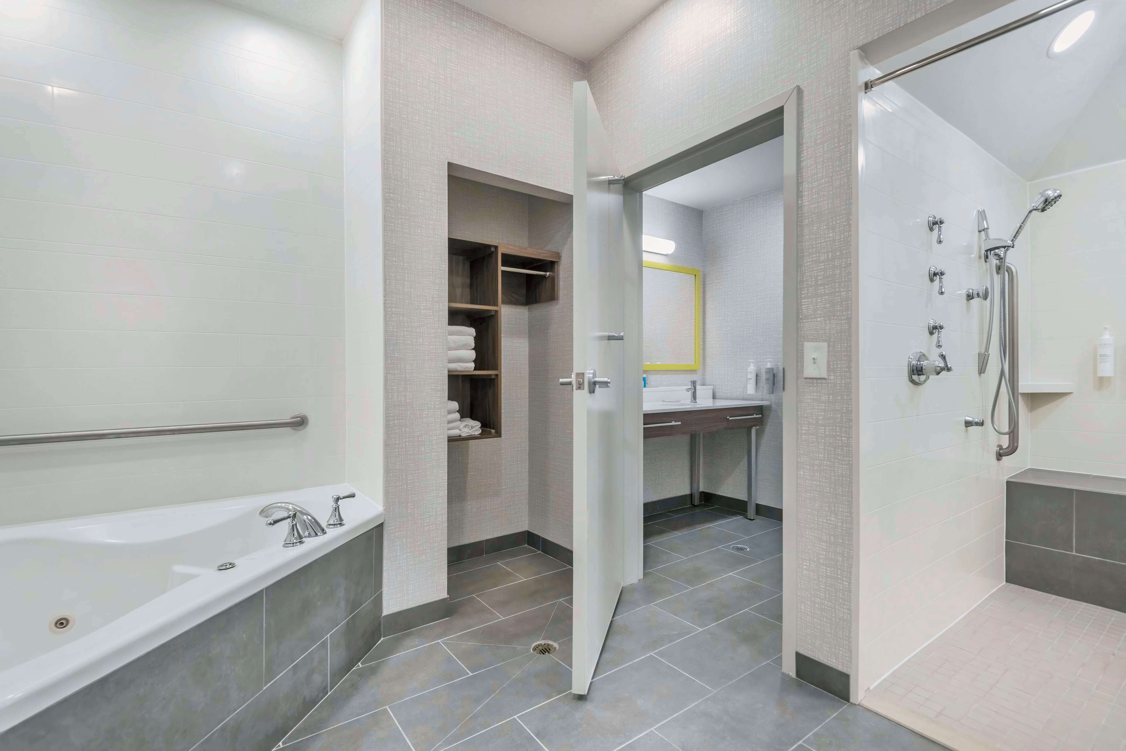 A modern bathroom with a bathtub, shower, and a vanity with a mirror.
