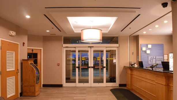 Un hall de hotel con mostrador de recepción, mostrador de madera, puerta de cristal de entrada y lámpara en el techo.