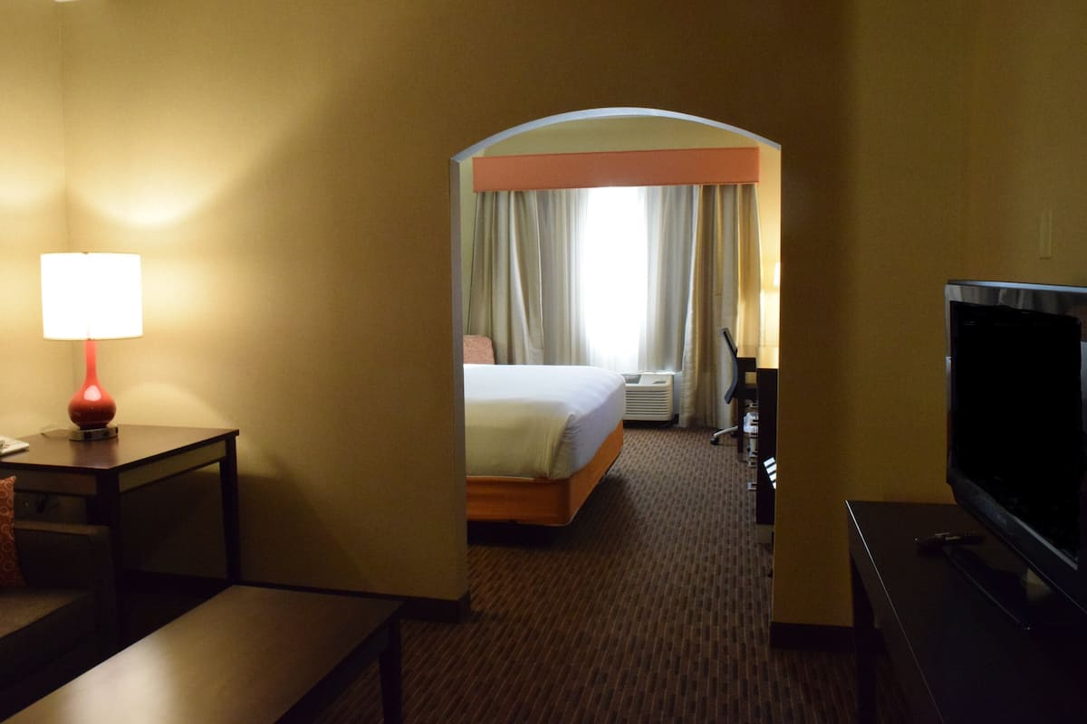 Una habitación de hotel con cama, televisión, lámpara y escritorio.