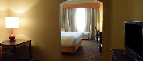 A hotel room with a bed, a TV, a lamp, and a desk.