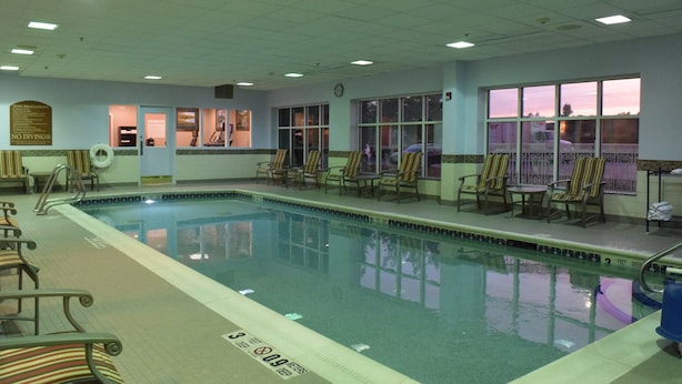Une piscine intérieure avec des chaises longues et une horloge au mur.