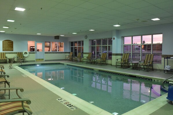 Une piscine intérieure avec des chaises longues et une horloge au mur.
