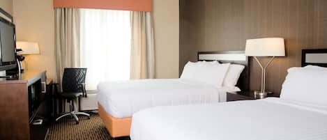 A hotel room with two beds, a desk with a computer, a chair, and a TV.