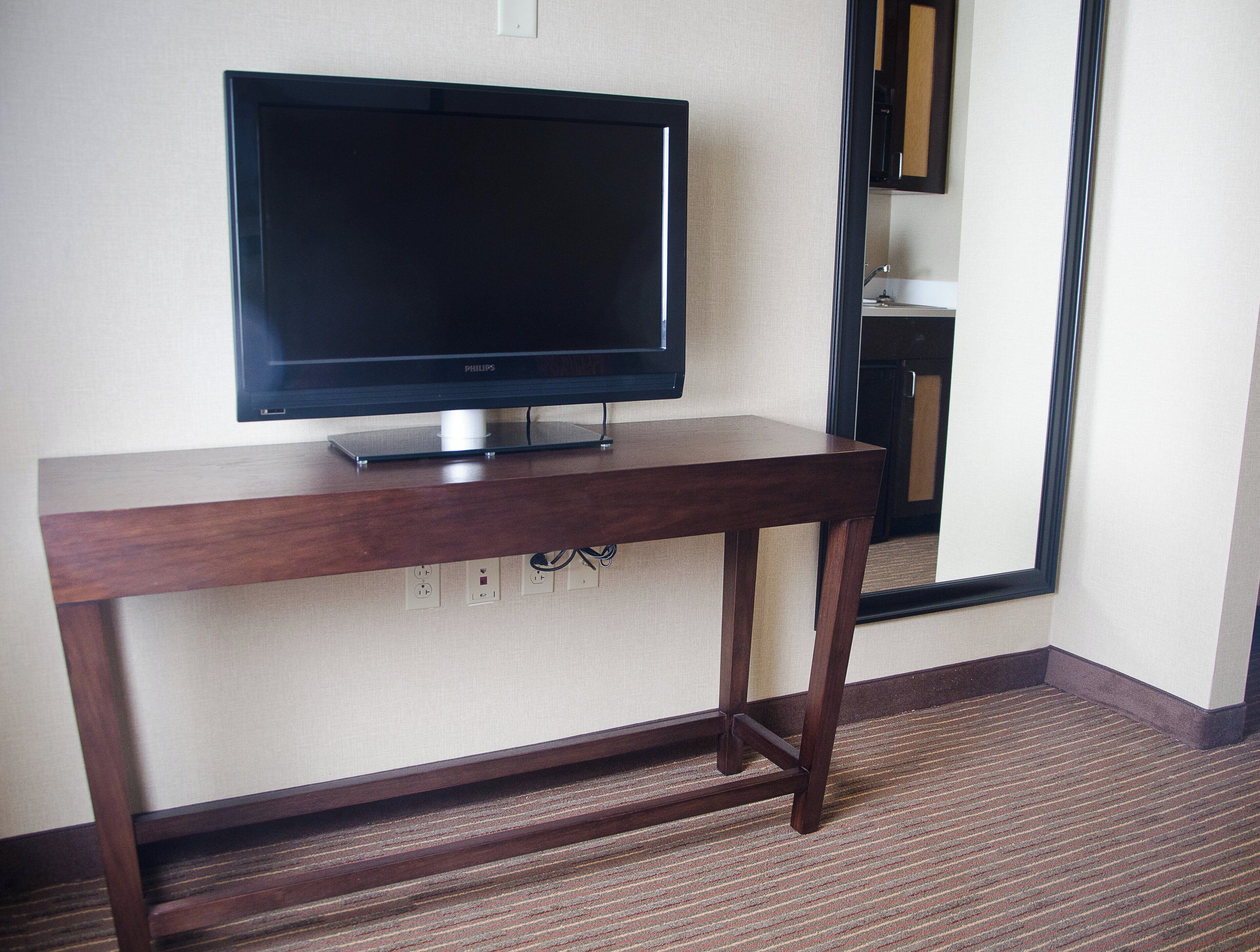 A television on a wooden stand in a hotel room.
