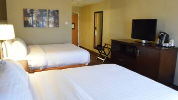 A hotel room with two beds, a television, a coffee machine, and a mirror.