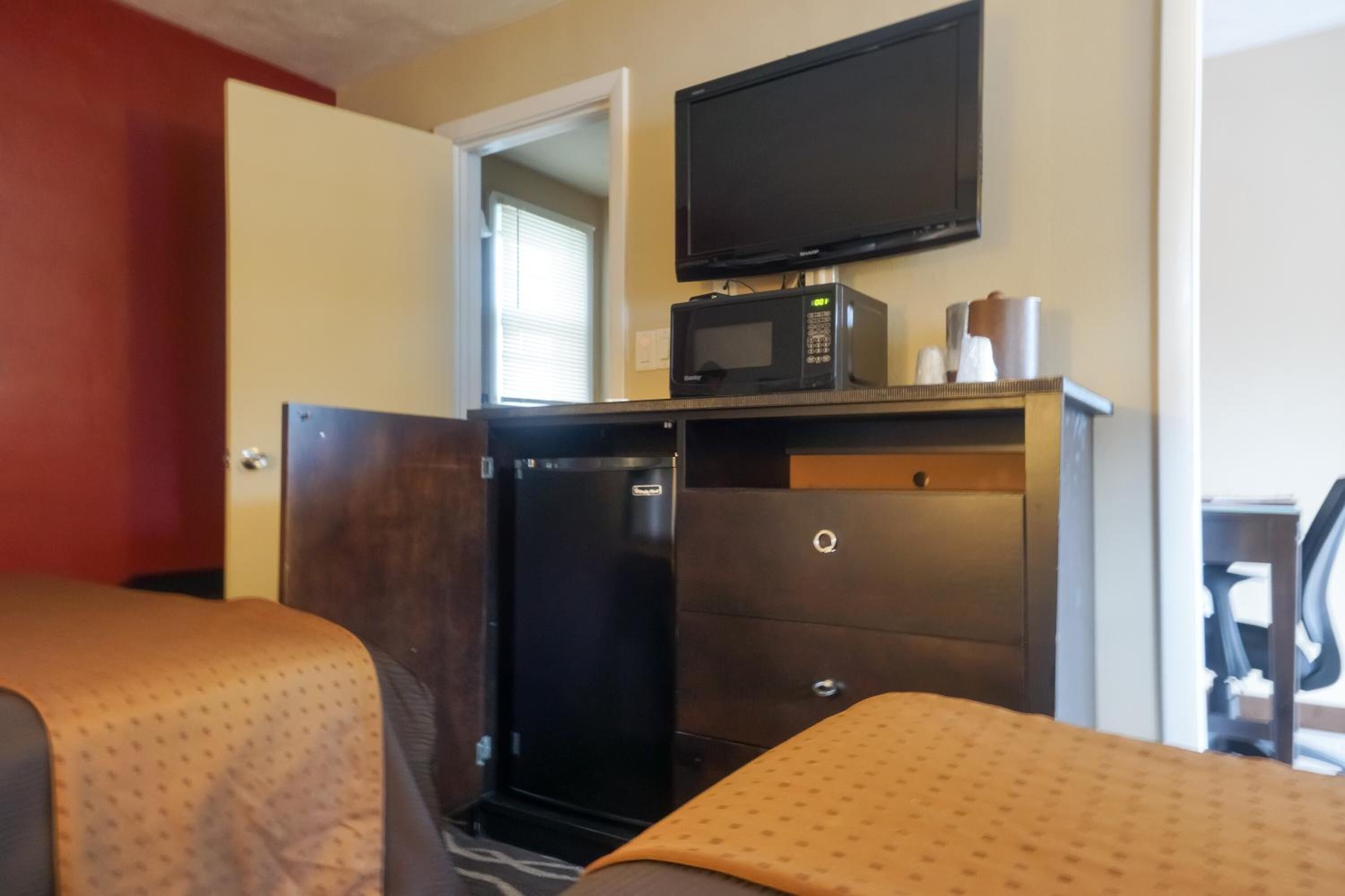 A hotel room with two beds, a television, a microwave, and a refrigerator.