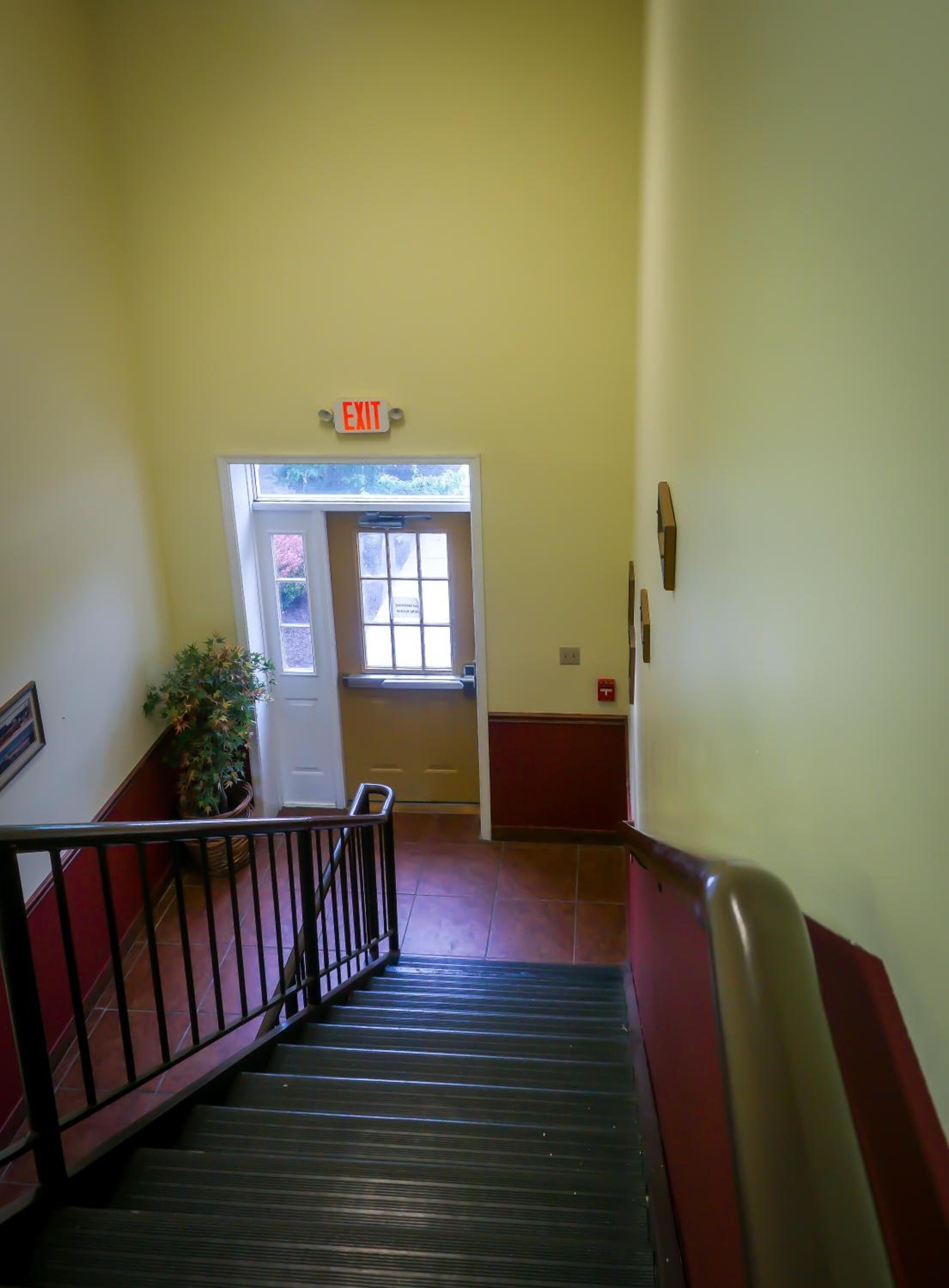 A staircase leading to an exit door with a sign above it.