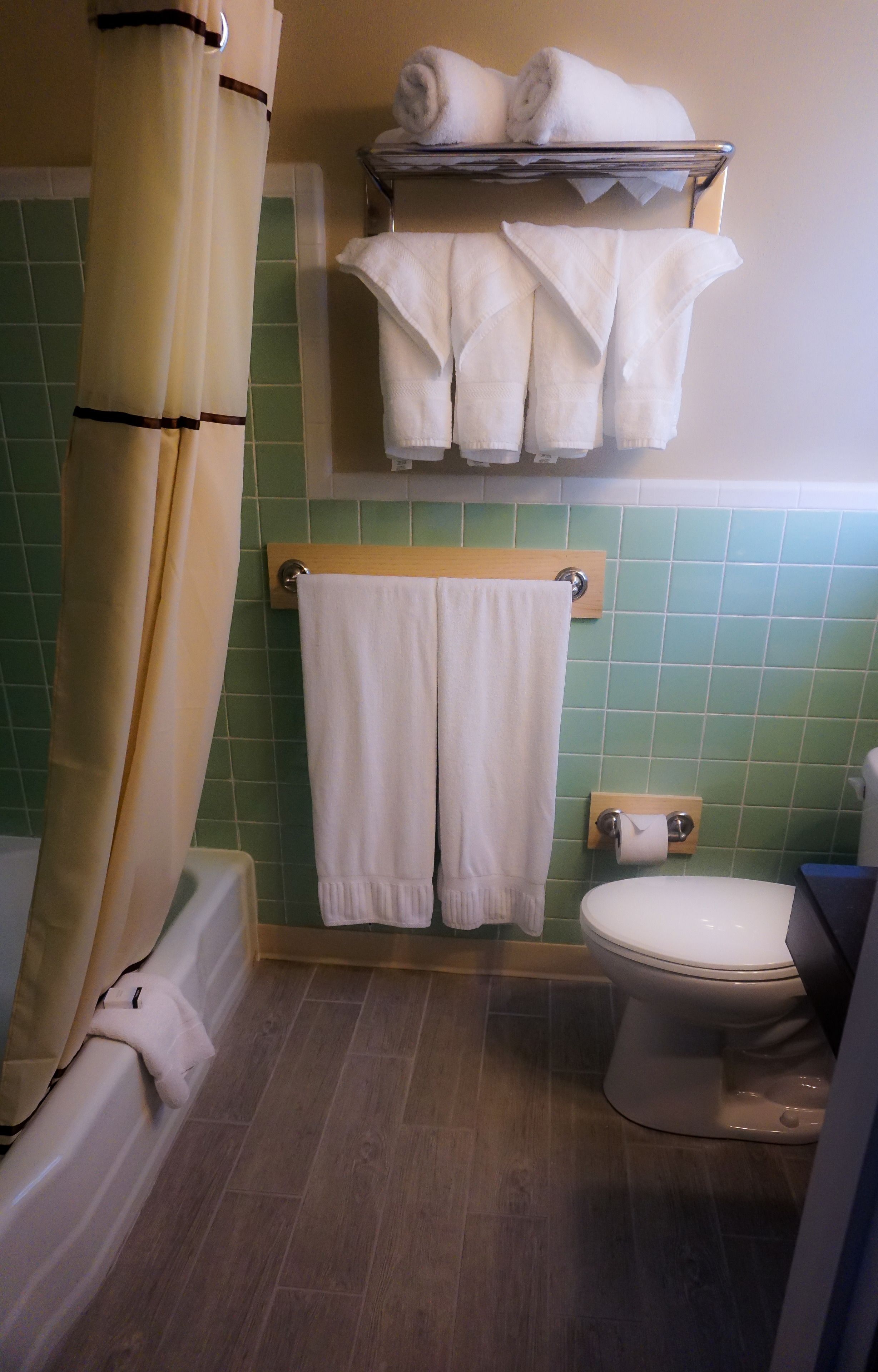 A bathroom with a bathtub, toilet, and a towel rack with towels.