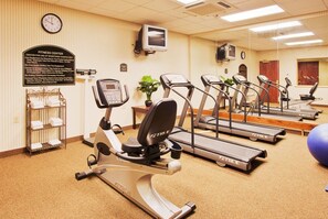 A fitness center with treadmills, an elliptical, and a wall clock.