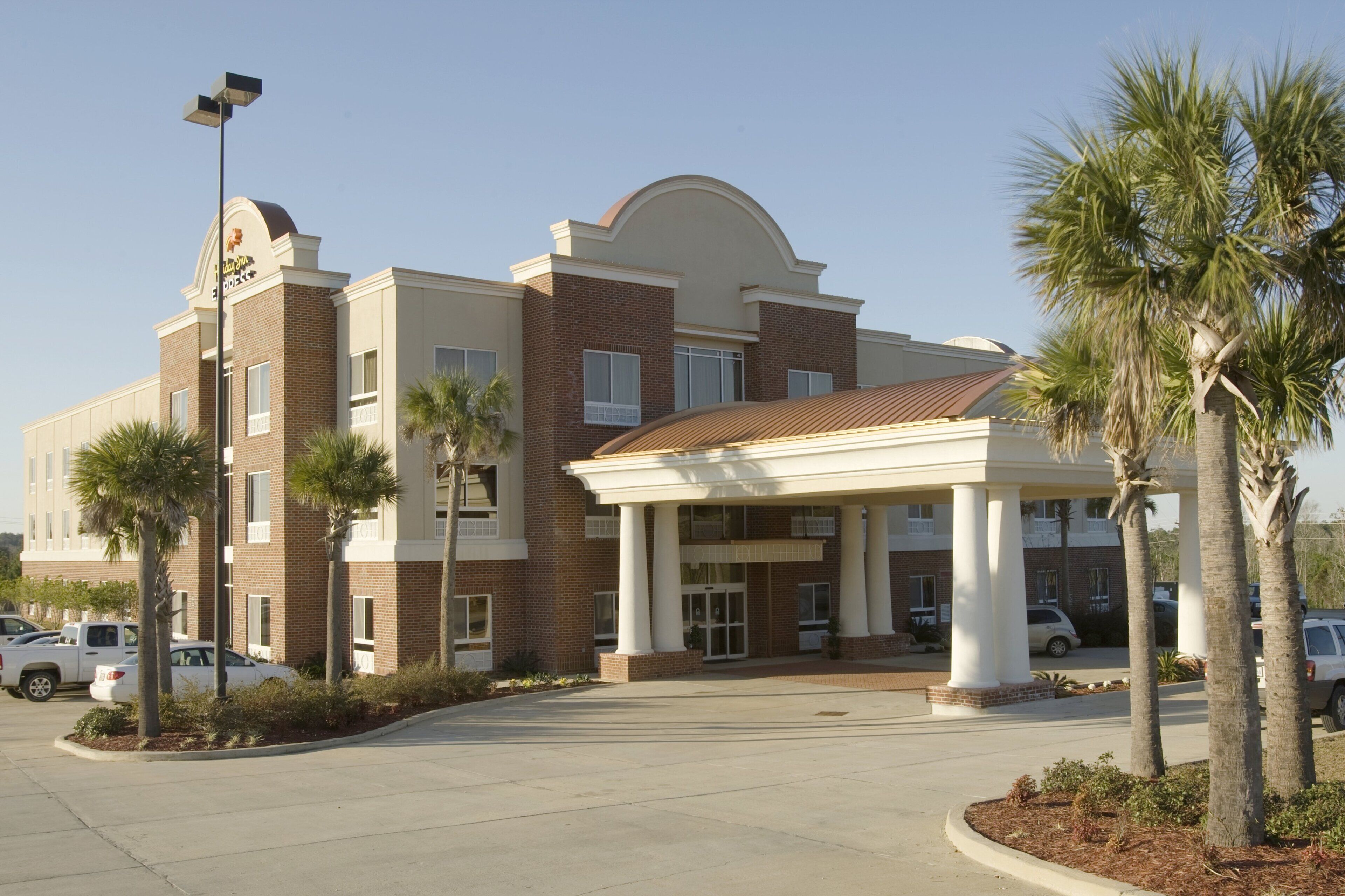A hotel with a central entrance, multiple floors, and a parking lot.