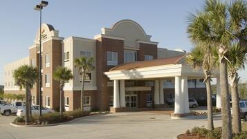 A hotel with a central entrance, multiple floors, and a parking lot.
