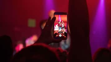 Une personne tenant un téléphone intelligent dont l’écran affiche une scène de concert.