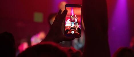 A person holding a smartphone with a concert scene visible on the screen.