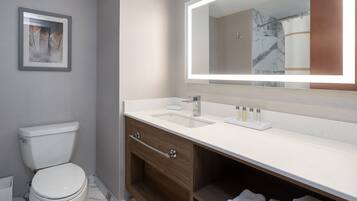 A modern bathroom with a toilet, vanity with a mirror, and a marble backsplash.
